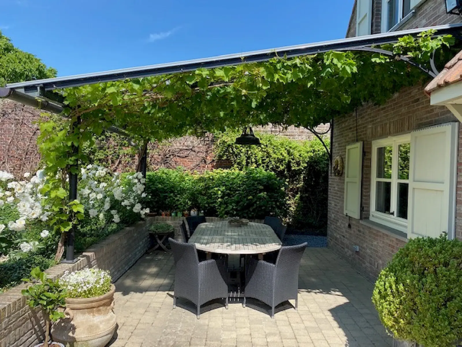Pergola en acier au-dessus d’une terrasse meublée