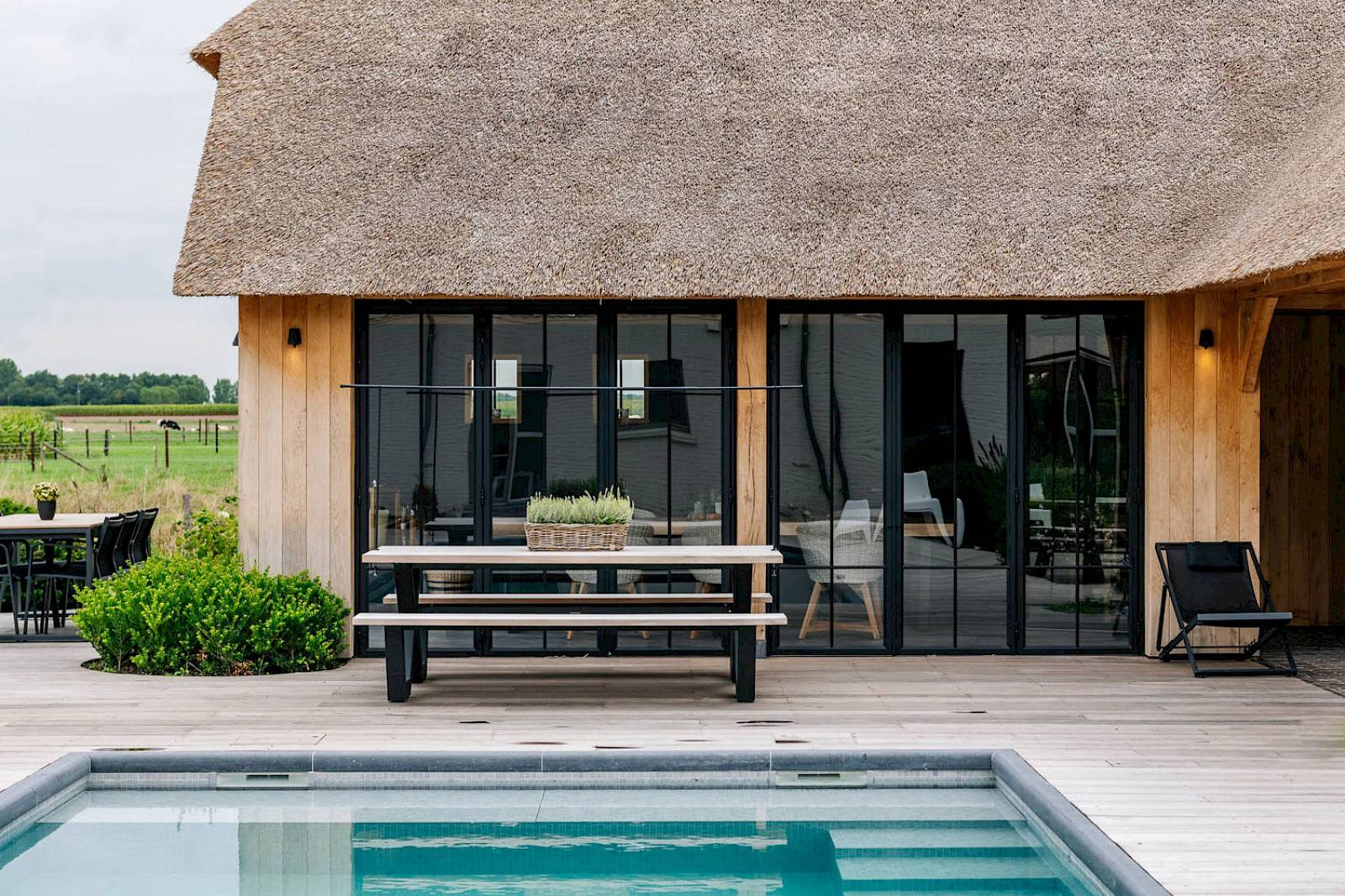 Pool house avec fenêtres en acier et auvent dans un jardin